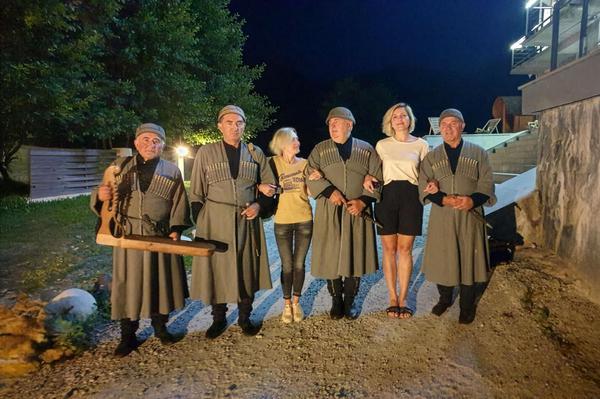 Guests posing with Svan musicians in traditional Georgian costumes after a live show in Mestia