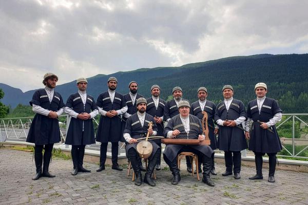 Svan male ensemble in traditional Georgian costumes with instruments in the mountains near Mestia