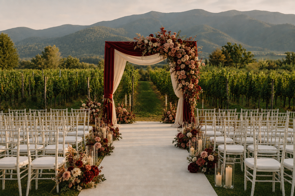 Burgundy floral wedding arch in a vineyard