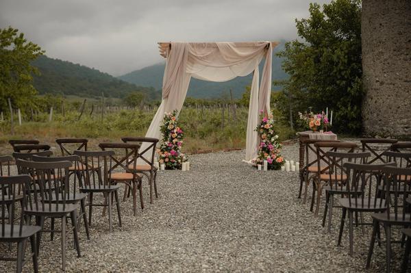 Vineyard ceremony setup with a draped wedding arch